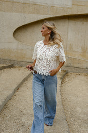 Blouse crochet manches courtes portée par une femme, silhouette entière, mains dans les poches