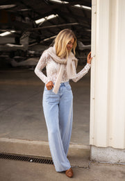 Blouse moulante en dentelle écrue portée par une femme, vue de face, hangar, jean large