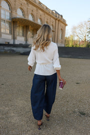 Blouse cache-cœur fluide portée par une femme, vue de dos, pantalon bleu marine, sur un chemin