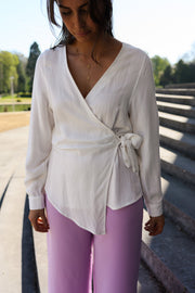 Blouse cache-cœur fluide portée par une femme, vue rapprochée, nœud sur le côté, pantalon rose