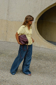 Blouse cintrée boutonnée manches courtes portée par une femme, silhouette entière, sac bordeaux à la main