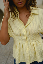 Blouse cintrée boutonnée manches courtes portée par une femme, vue rapprochée, main dans les cheveux