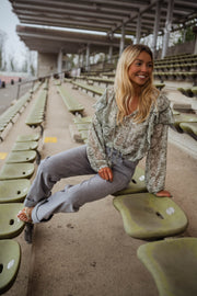 Blouse volantée à col V portée par une femme, assise, gradins, jambes croisées
