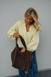 Blouse douce ample boutonnée portée par une femme, vue rapprochée, sac marron