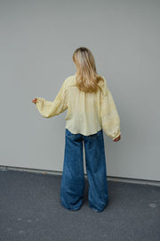 Blouse douce ample boutonnée portée par une femme, vue de dos, bras écartés