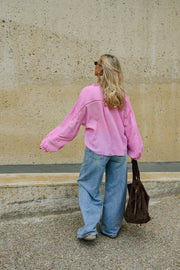 Blouse boutonnée à manches évasées portée par une femme, vue de dos, silhouette entière, bras écarté