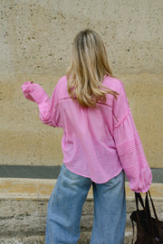 Blouse boutonnée à manches évasées portée par une femme, vue de dos, bras levé