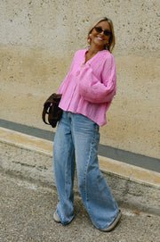 Blouse boutonnée à manches évasées portée par une femme, silhouette entière, lunettes de soleil, sac à l'épaule
