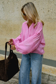 Blouse boutonnée à manches évasées portée par une femme, vue de trois-quarts, sac marron à la main