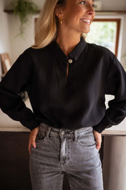 Blouse gaufrée à boutons noire portée par une femme, vue rapprochée, cuisine, jean