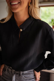 Blouse gaufrée à boutons noire portée par une femme, vue rapprochée, boutons, jean