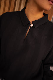 Blouse gaufrée à boutons noire portée par une femme, vue rapprochée, col, bouton