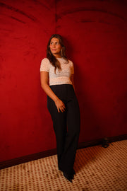 Blouse smockée à col rond écrue portée par une femme, vue de face, mur rouge, pantalon noir