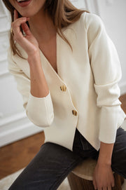 Blouse moulante à boutons dorés écrue portée par une femme, vue rapprochée, encolure, main sur la hanche