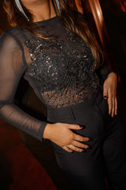 Body perlé à dos ouvert noir porté par une femme, vue rapprochée, perles, main sur le ventre