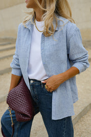 Chemise épaisse col classique portée par une femme, vue rapprochée, sac bordeaux, chemise ouverte