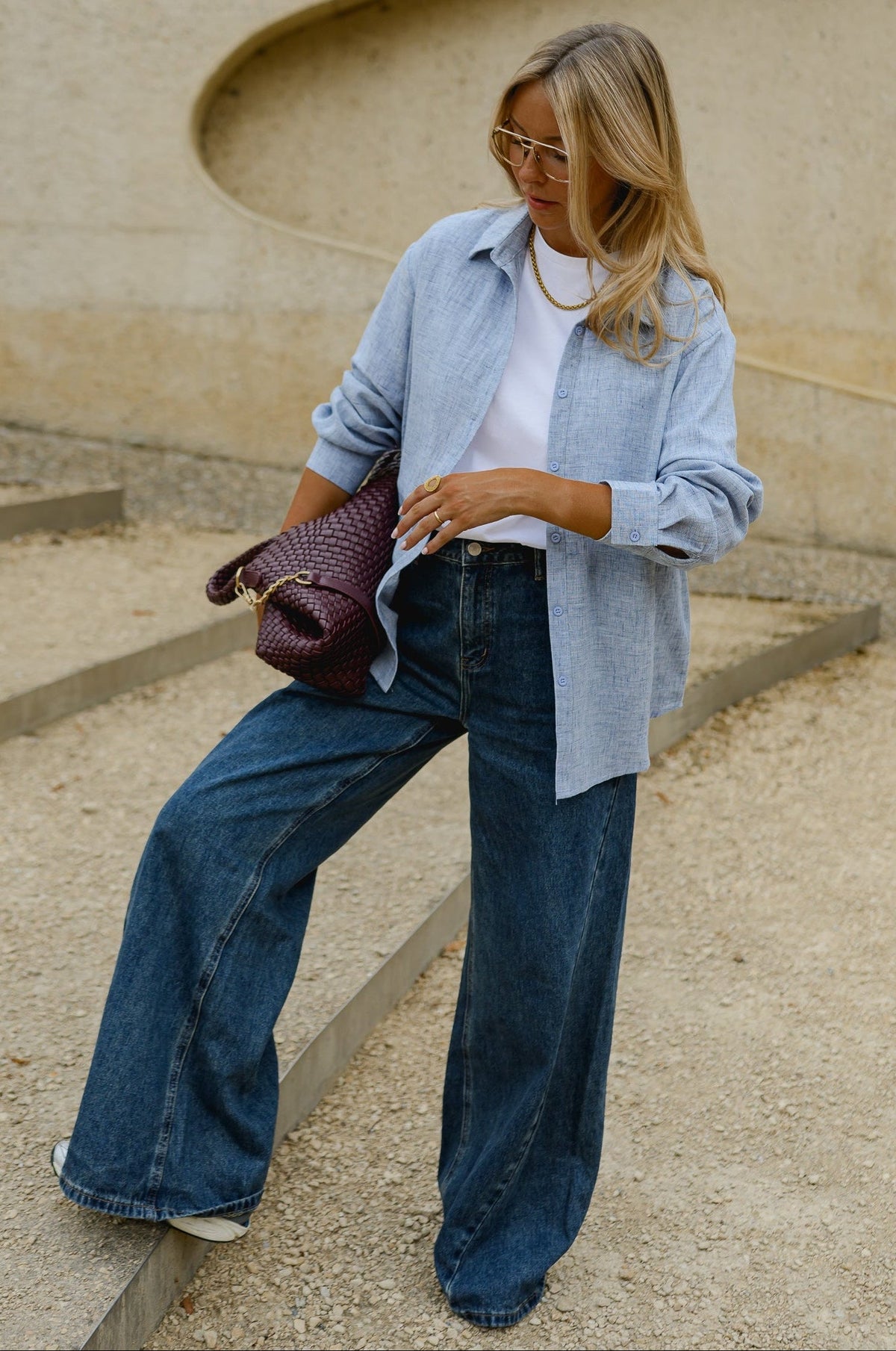 Chemise épaisse col classique portée par une femme, vue de trois-quarts, sac bordeaux à la main