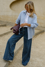 Chemise épaisse col classique portée par une femme, vue de trois-quarts, sac bordeaux à la main