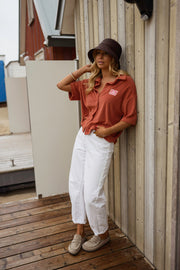 Chemise éponge loose portée par une femme, silhouette entière, pantalon blanc, cabine