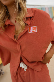 Chemise éponge loose portée par une femme, vue rapprochée, étiquette, cordon