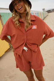 Chemise éponge loose portée par une femme, vue de trois-quarts, short assorti, plage