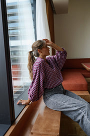 Chemise à carreaux col chemise portée par une femme, assise, sur un banc, main dans les cheveux
