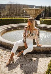 Chemise imprimée manches longues portée par une femme, assise, fontaine, pantalon blanc