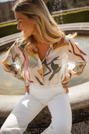 Chemise imprimée manches longues portée par une femme, vue de trois-quarts, fontaine, pantalon blanc
