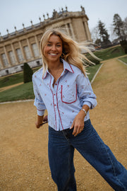 Chemise rayée brodée à cerises portée par une femme, vue de face, sourire, jardin