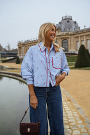 Chemise rayée brodée à cerises portée par une femme, vue de face, bassin, sac bordeaux