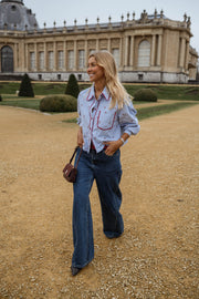 Chemise rayée brodée à cerises portée par une femme, en marchant, palais, jean large