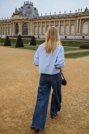 Chemise rayée brodée à cerises portée par une femme, vue de dos, esplanade, cheveux blonds