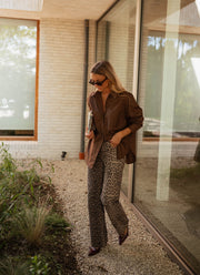 Chemise manches longues loose chocolat portée par une femme, silhouette entière, allée, pantalon léopard