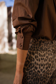 Chemise manches longues loose chocolat portée par une femme, vue rapprochée, manche, pantalon léopard