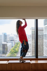 Chemise ample à manches longues rouge portée par une femme, vue de dos, bras levés