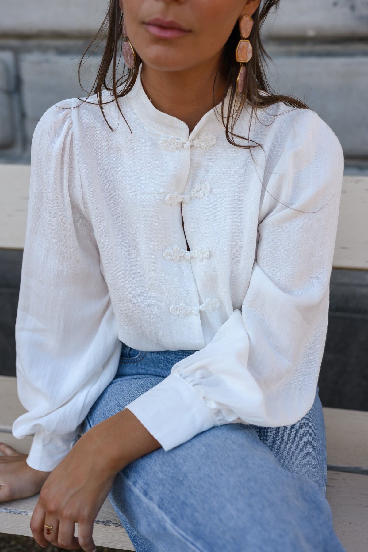 Chemise transparente à brandebourgs portée par une femme, vue rapprochée, assise, jean