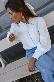 Chemise transparente à brandebourgs portée par une femme, assise, sur un banc, vue de trois-quarts