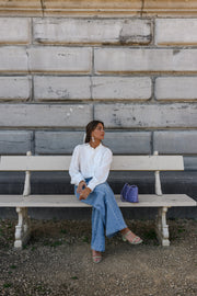 Chemise transparente à brandebourgs portée par une femme, assise, sur un banc, vue de loin