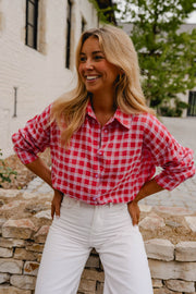 Chemise à carreaux brillante portée par une femme, vue rapprochée, pantalon blanc, mains sur les hanches