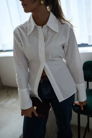 Chemise cintrée à nouer blanche portée par une femme, vue rapprochée, col pointu, jean foncé