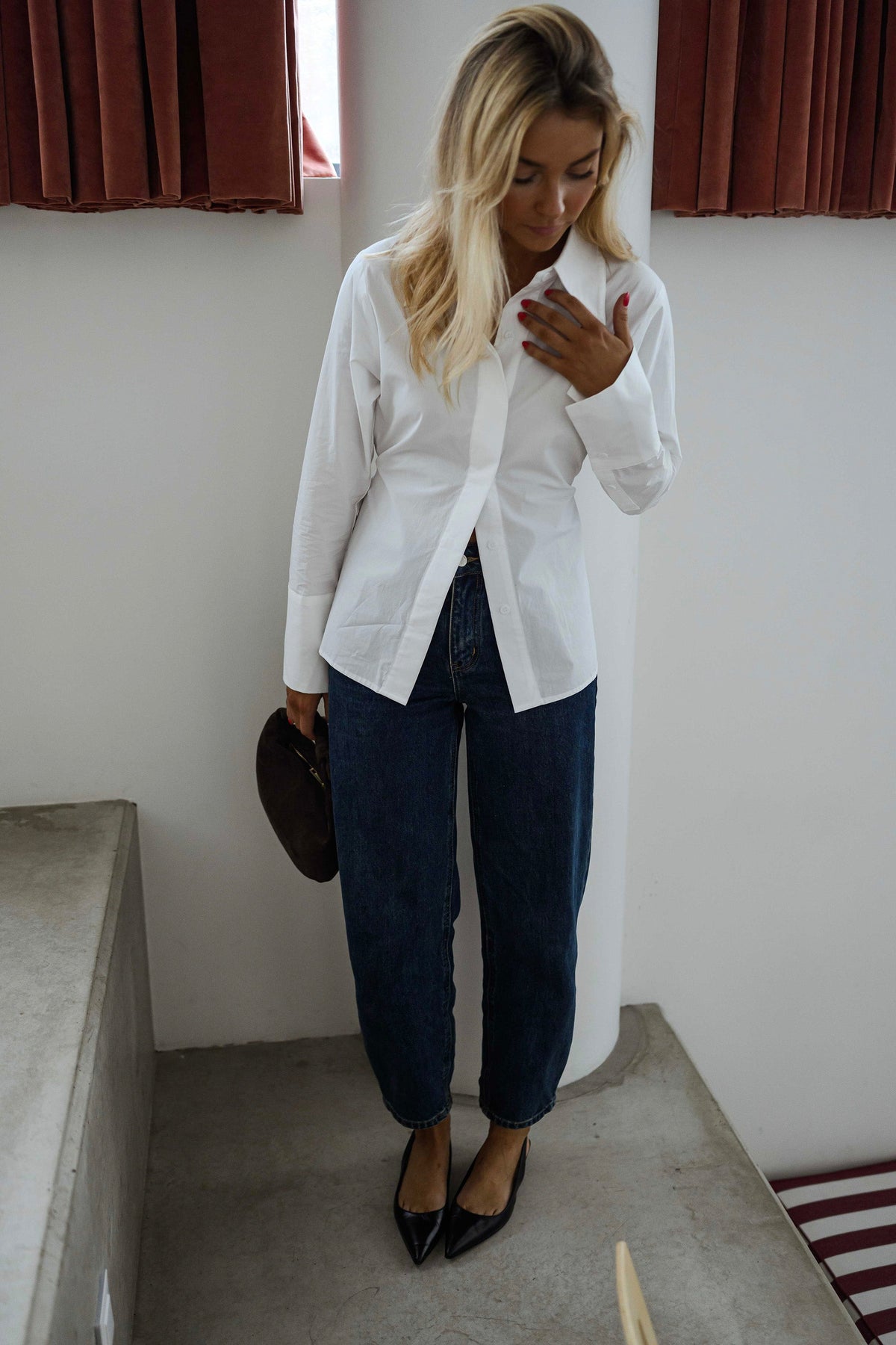 Chemise cintrée à nouer blanche portée par une femme, vue de face, escalier, sac noir