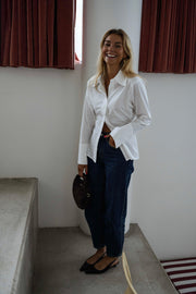 Chemise cintrée à nouer blanche portée par une femme, vue de face, escalier, sac noir clair