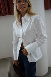 Chemise cintrée à nouer blanche portée par une femme, vue de face, colonne blanche, jean bleu