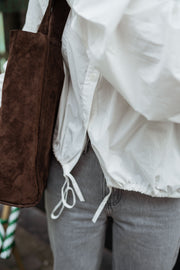 Chemise courte à poches blanche portée par une femme, vue rapprochée, cordons, sac