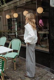 Chemise courte à poches blanche portée par une femme, silhouette entière, vitrine, chaises