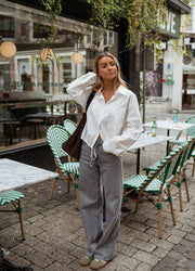 Chemise courte à poches blanche portée par une femme, vue de face, terrasse, sac