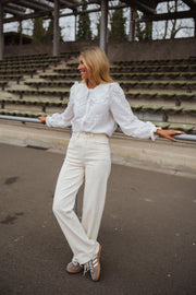 Chemise brodée col claudine blanche portée par une femme, vue de face, gradins, pas de côté