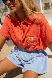 Chemise fluide à plumetis corail portée par une femme, vue rapprochée, col, poche