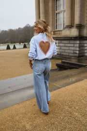 Chemise rayée dos cœur ouvert portée par une femme, vue de dos, allée sablée, découpe en cœur