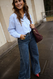 Chemise rayée dos cœur ouvert portée par une femme, vue de trois-quarts, sac bordeaux, jean large